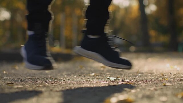 Cardio workout, Close up of male athlete legs jumping jack and training in sunny autumn park at sunset