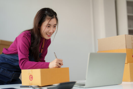 Young asian woman packing parcel for online business
