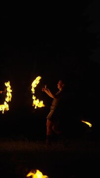 Nighttime fire dancer performing swirling flame choreography in the darkness, creating glowing trails of light with dynamic movement and spinning artistry
