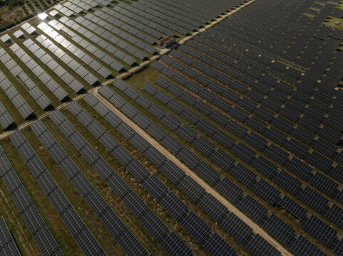 Aerial view of a vast solar panel farm with rows of photovoltaic modules reflecting sunlight in Priolo Gargallo, Sicily, Italy.
