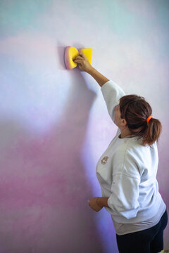 Artist painting a rainbow cloud mural in a girls bedroom