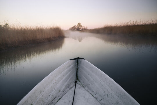 View from rowing boat on misty river at tranquil sunrise in nature