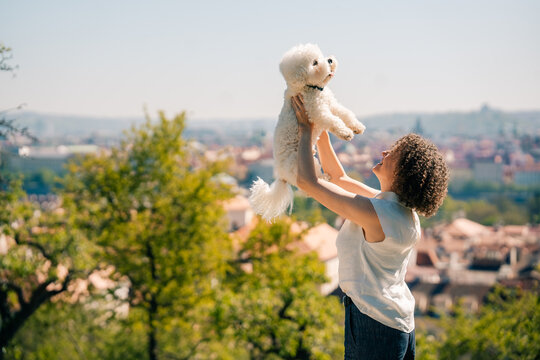 Woman holds Bichon Frise dog in Prague with city view