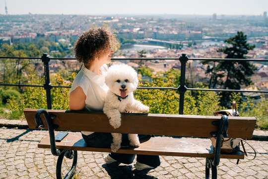 Bichon Frise and owner enjoy a sunny day in Prague on a bench