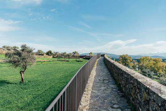 Stone walkway along fortress wall leading through rural landscape