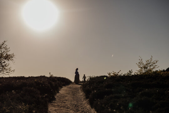 Pregnant mother walking with child at sunset