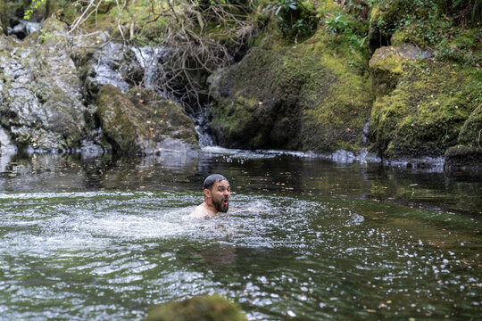 Man wild swimming in cold forest stream