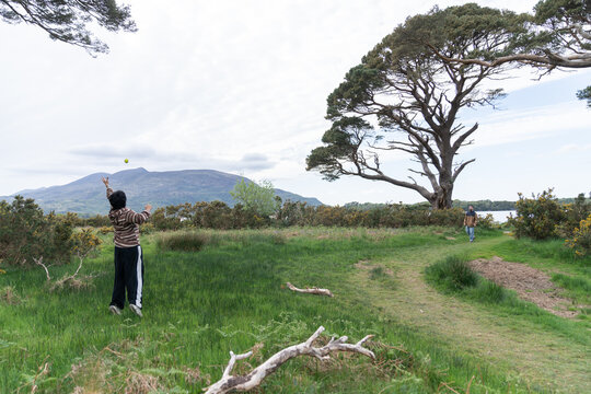 Child playing with ball in green natural landscape