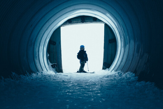 Young skier stands at the end of a snow tunnel