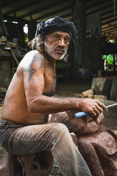 Polynesian man carving a traditional stone sculpture