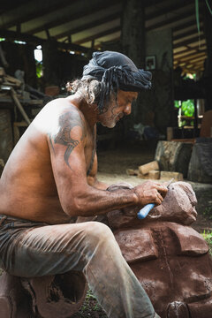Polynesian artisan carving a traditional stone sculpture