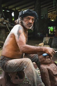 Mature tattooed artisan carving a stone sculpture