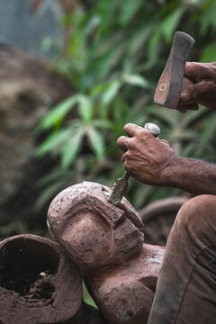 Artist hands carving a terracotta sculpture outdoors