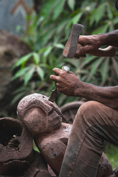 Artisan carving a statue with traditional tools