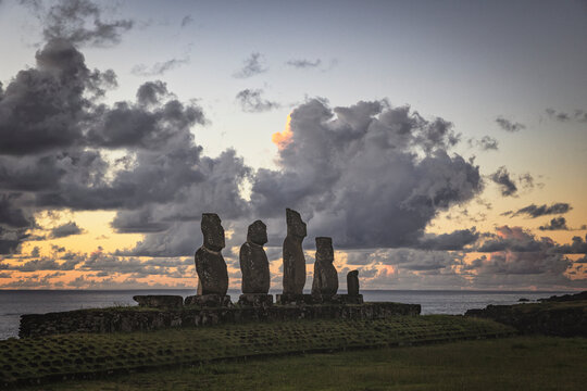 Moai statues on Easter Island under a dramatic sky at sunset