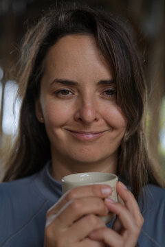 Smiling woman holding ceramic coffee cup, Munduk, Bali