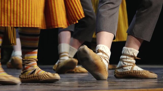 Close-up of dancers' feet in soft leather shoes and white socks performing on a stage, capturing movement, rhythm, and traditional folk dance.
