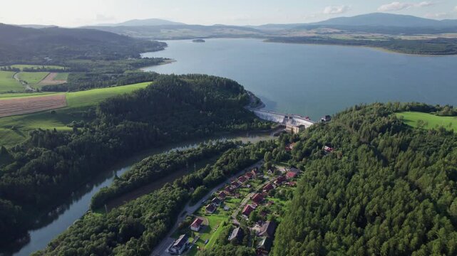 Hydroelectric power plant and dam surrounded by forest and reservoir aerial view