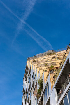 Blue sky opens above a Paris building corner in Rive Gauche, where white facade lines and balconies hold the afternoon light across upper floors.