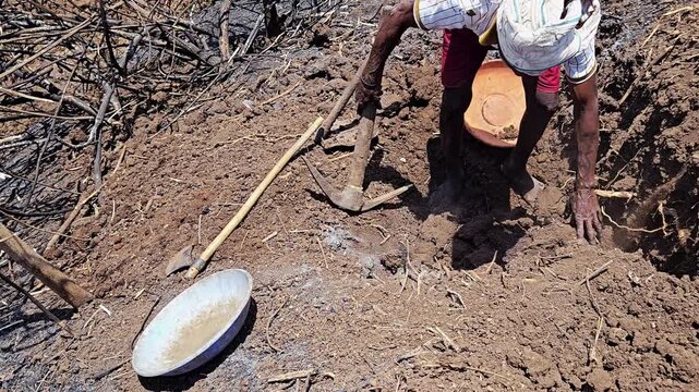 Basking in bright sunlight, a laborer commits to hard work by digging deep trenches. Resolving this agriculture pipeline leakage leaves them sweating under the intense daytime heat.