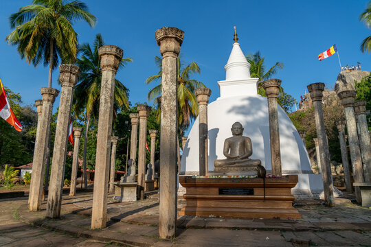 White stupa surrounded by stone columns and Buddha statue, Mihintale, Sri Lanka