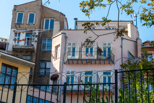 A pink building with a balcony behind barbed wire.