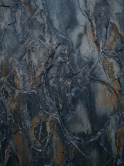 Fototapeta premium Close-up of a dark, weathered rock surface with intricate cracks and swirling patterns in shades of blue, gray, and brown, showcasing natural geological textures.