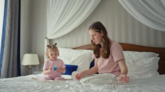Young mother spending quality time with her toddler daughter, playing educational games together in a cozy bedroom, fostering early development and strengthening their family bond at home