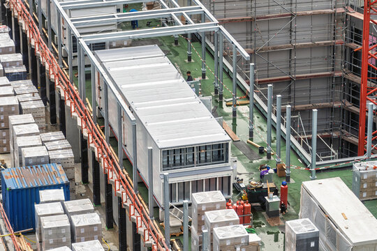 Aerial view of a busy construction site with rooftop packaged unit or RTU, scaffolding and stacked building materials.