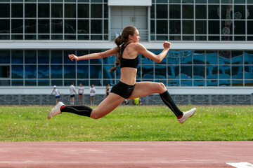 Obraz premium Beautiful female athlete triple jump at stadium
