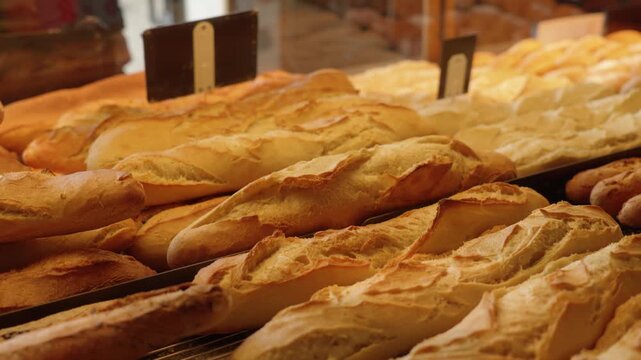 Fresh baguettes displayed on bakery shelves under warm lighting, ready for sale