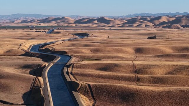 Water flowing through the arid desert of the California Aqueduct canals. Wide landscape of agricultural man-made river delivering water to agricultural farmlands for irrigation in rural farmlands.