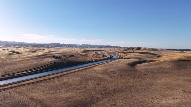 Water flowing through the deserts of the Aqueduct canals. Wide landscape of agricultural man-made river delivering water to agricultural farmlands for irrigation in rural farmlands.