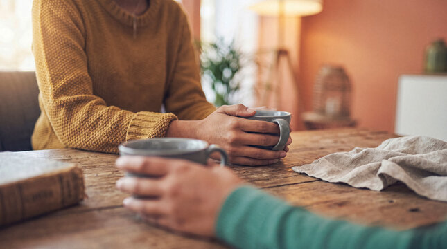 Two pairs of hands holding warm coffee mugs on a rustic wooden table, symbolizing connection and shared moments.
