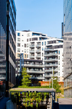 Residential apartment building appears beyond a planted balcony in Loren as glass facade edges frame urban architecture in Oslo, Norway