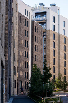 Narrow courtyard runs beside a residential apartment building in Loren where brick facade and balcony levels shape urban architecture in Oslo, Norway
