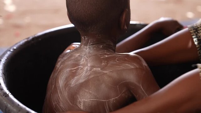 Close up of child being washed by mother in Africa, April 25, 2026, Chad, N Djamena