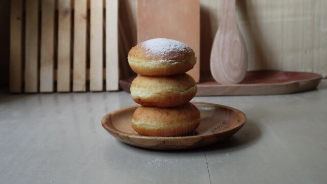 Hand pouring dusting sugar on fresh donuts
