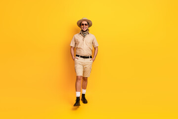 Man in safari outfit stands against bright yellow background ready for adventure and travel © deagreez