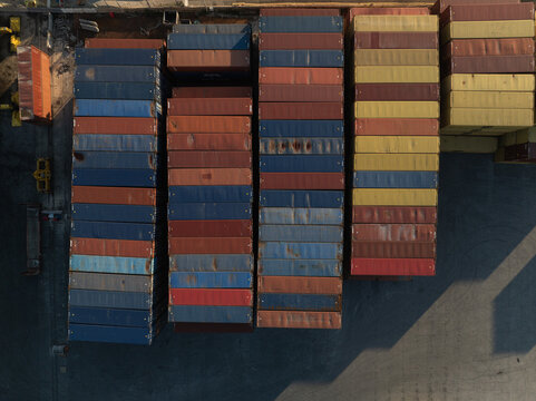 Aerial view of stacked multi-colored shipping containers in a commercial port during sunset Augusta, Sicily, Italy.