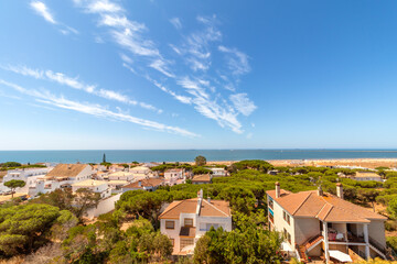 Obraz premium Elevated view of Mazagon beach town with white houses, green pine forest and blue sea. Summer landscape of Huelva coast in Andalusia, Spain.