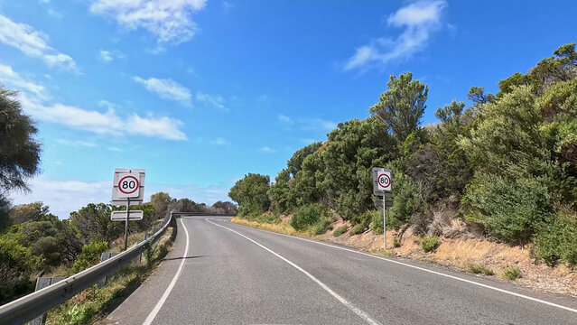 Winding asphalt road with speed limit signs on Great Ocean Road Australia