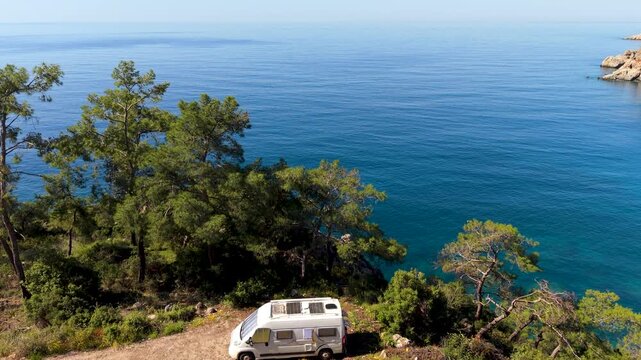 Admire the breathtaking view of Kargili Creek Beach in Mavikent, Antalya. A serene escape awaits with crystal-clear waters and lush greenery, A camper van or rv parked with ocean view
