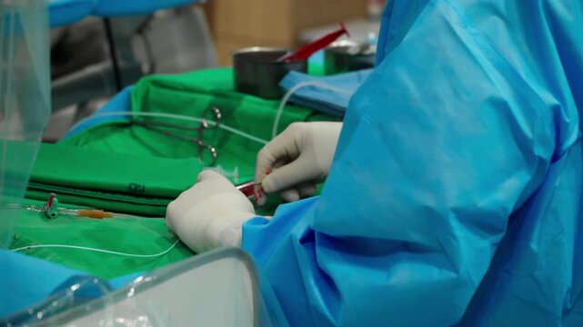 Surgical clamps and medical equipment on green surgical tray inside operating room.