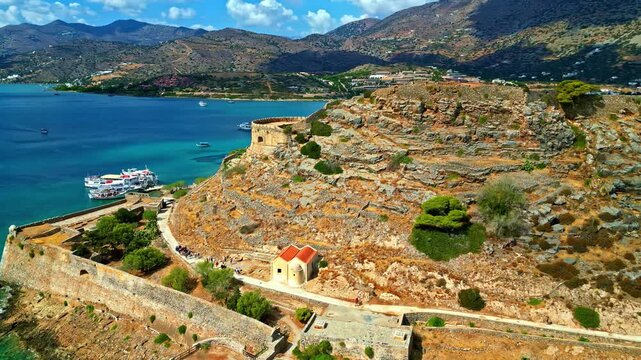Ancient fortress on rocky coastline with clear sea and mountains in background