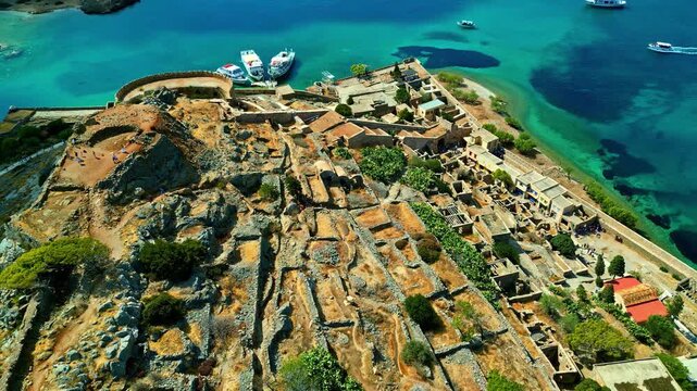 Aerial view of Spinalonga island fortress surrounded by turquoise sea and rocky coastline