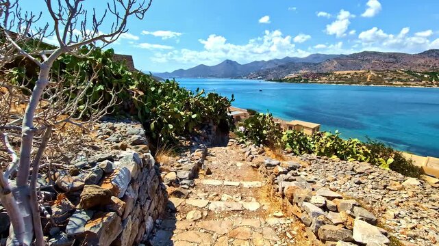 Stone pathway at Spinalonga Fortress with sea and clear sky in background