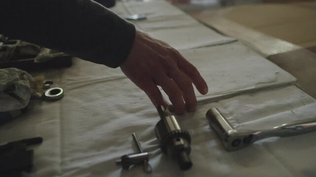 A slow motion shot of a mechanic opening an flipping through their blueprint, spec book on their workbench surrounded by tools in their workshop