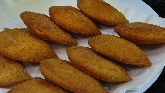 Fried Portuguese rissois, a traditional appetizer, served on a plate lined with paper towel.