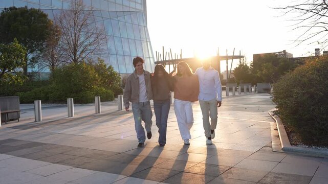 Multicultural young people walking together in an urban park. Happy friends enjoying a beautiful sunset with lens flare, representing fun